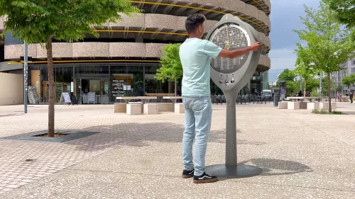 Gouvernail installé sur une place piétonne, piéton qui l'utilise pour trouver son chemin